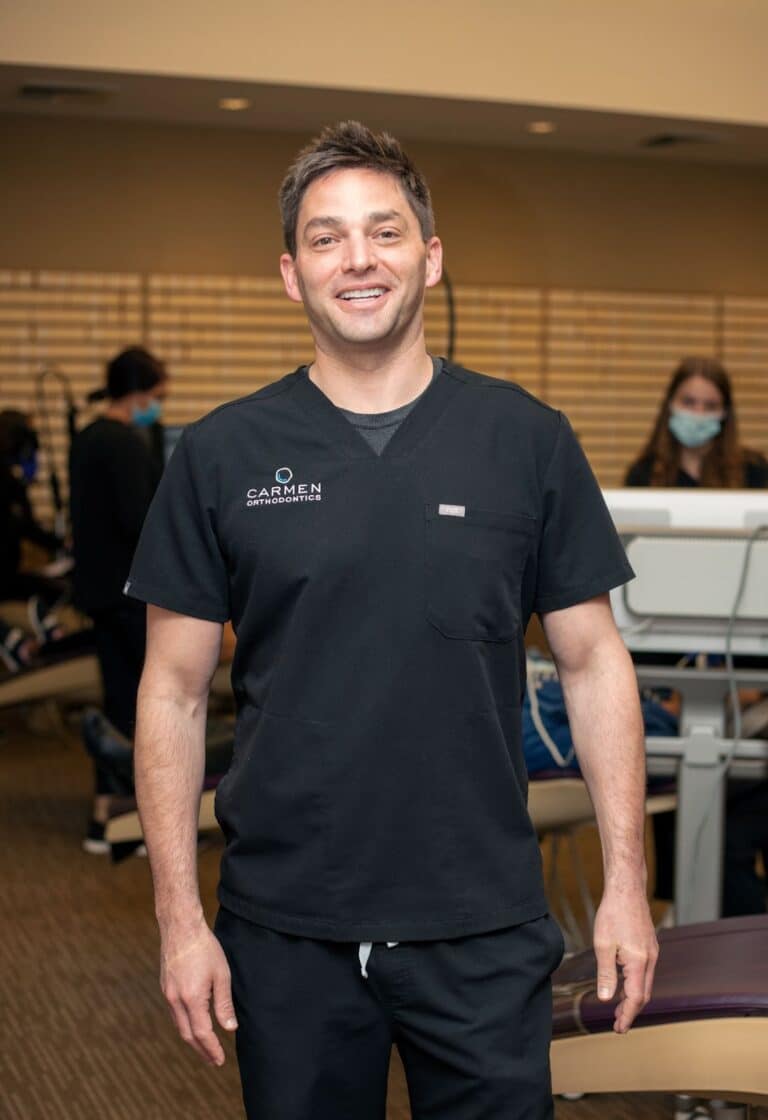 Orthodontist near Gahanna Ohio Dr. Jesse Carmen smiling in his black Carmen Orthodontics scrubs